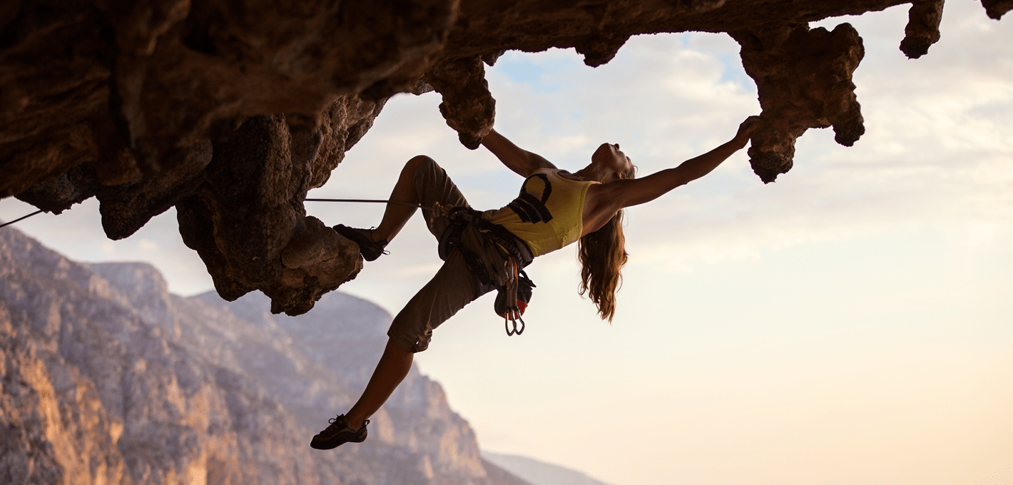 A climber leading a dynamic overhanging climb