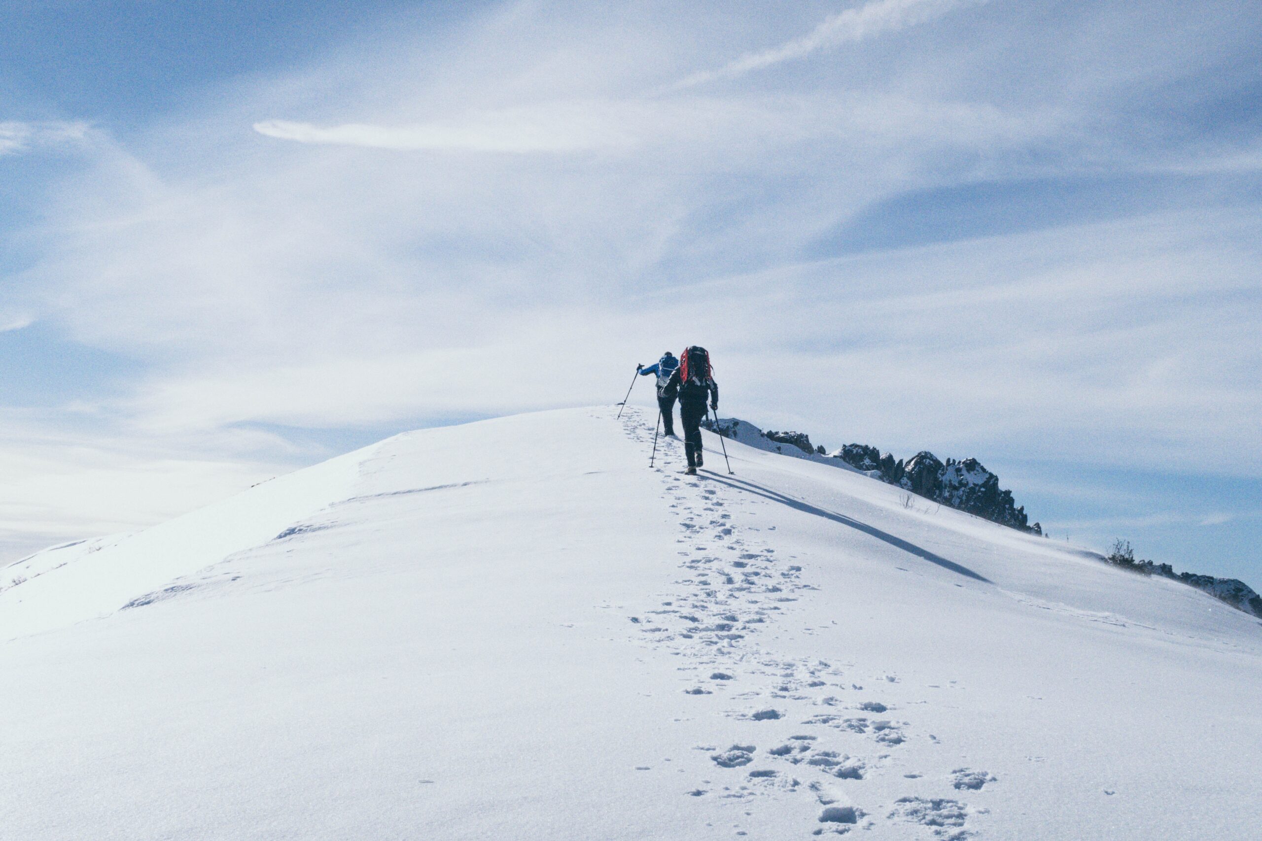 Two people hiking up a snowy slope